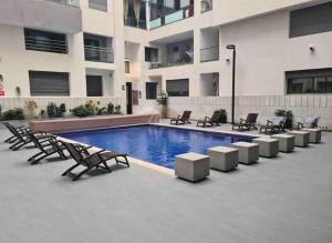 a swimming pool with chairs and a building at Miramar Luxury apartment Front Beach View in Mohammedia