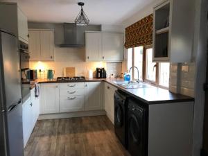 a kitchen with white cabinets and a washer and dryer at River Airebnb in Bradford