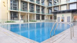 a large building with a large blue swimming pool at Opulent 2BR Duplex Apartment in Abu Dhabi