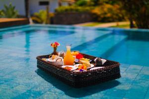 a tray of snacks and a drink next to a swimming pool at Pousada Reserva do Patacho in Pôrto de Pedras