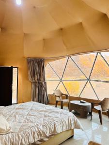 um quarto com uma cama e uma grande janela em Amir Rum luxury tents em Wadi Rum