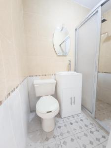 uma casa de banho branca com um WC e um espelho. em Esquina del Pintor em Guadalajara