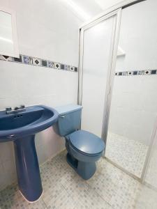 y baño con aseo azul y lavamanos. en Esquina del Pintor, en Guadalajara
