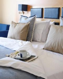 新卡利克拉蒂業的住宿－愛琴海藍色海灘酒店=，白色的床,盘子上放着咖啡