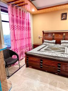 1 dormitorio con 1 cama, 1 silla y 1 ventana en Vacations In en Nathia Gali
