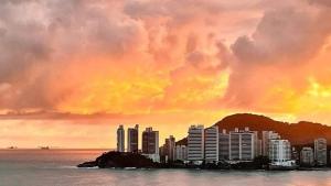a painting of a city in the water at sunset at Ap 2 quartos suite wifi 30m da praia in Guarujá