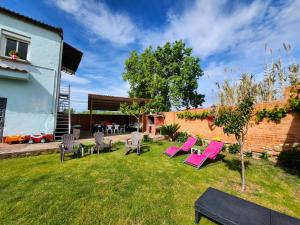 un patio trasero con sillas rosas y una mesa en Casa Azul donde se respira tranquilidad, en Lardero