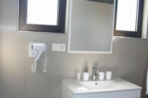 een badkamer met een witte wastafel en een spiegel bij The View Hotel in Tongon