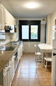 een keuken met witte kasten en een tafel en stoelen bij Apartamento céntrico en la playa de Bueu in Bueu