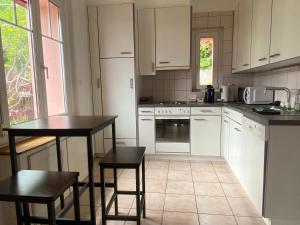 a kitchen with white cabinets and a table and chairs at Chez Carole (4 pièces) in Neuchâtel