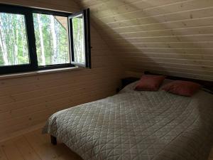 a bed in a room with two windows at Leśne Klimaty in Smolniki