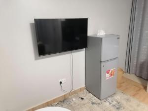a flat screen tv hanging on a wall with a refrigerator at Sunny Homestays in Nairobi