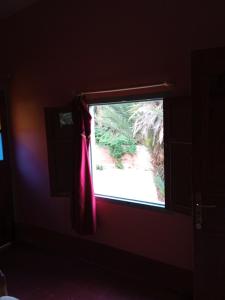 a window with a red curtain in a room at Auberge Camping Garde of Eden LE LAC in Tinerhir