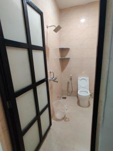 a bathroom with a toilet and a shower and a door at Hotel MJ baga in Calangute