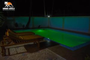 una piscina con luz verde en un patio trasero por la noche en Shikari Luxville, en Vipingo