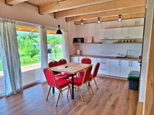 a kitchen with a wooden table and red chairs at Zefirowe Wzgórze in Polańczyk