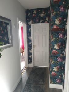 キャリック・オン・シャノンにあるHillside Residenceの白いドアと花の壁紙の廊下