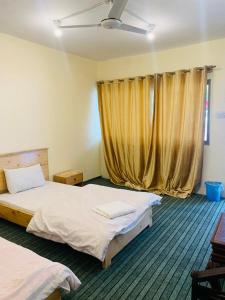 a bedroom with two beds and a window with curtains at Hotel Travel Lodge in Skardu