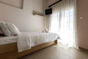 Ayiá的住宿－Melivoia Apartment，一间卧室配有一张带白色床单的床和一扇窗户。