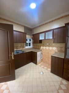 cocina grande con armarios de madera y suelo de baldosa en Queen Apartment en Amán