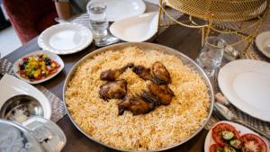 a table with a plate of food with chicken on rice at Queen Apartment in Amman