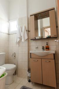 y baño con lavabo, aseo y espejo. en Melivoia Apartment, en Ayiá
