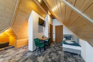 - une chambre avec un lit et un bureau dans une chambre dotée de plafonds en bois dans l'établissement Willa Folk Prestige, à Zakopane