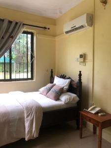 a bedroom with a bed and a window with a air conditioner at CBA Hotel in Tanga