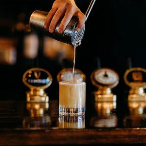 een barman maakt een drankje op een bar bij The Crown Inn in Chiddingfold