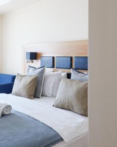 uma cama grande com almofadas brancas em Aegean Blue Beach Hotel em Nea Kalikratia