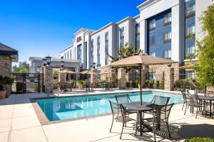a hotel patio with a table and chairs and a pool at Hampton Inn & Suites Manteca in Manteca