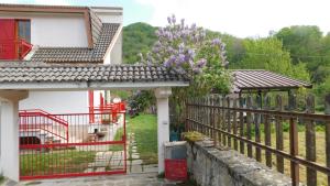 una casa con un cancello rosso e un albero con fiori viola di Casa BnB Pappappero Monti della Laga a Fioli