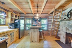 a kitchen with wooden walls and wooden floors and a fireplace at Restored Buchanan Log Cabin on 9-Mile Creek! in Reba