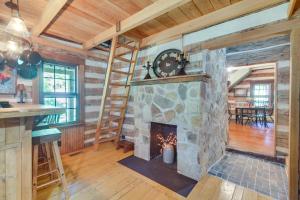 a living room with a stone fireplace in a log cabin at Restored Buchanan Log Cabin on 9-Mile Creek! in Reba