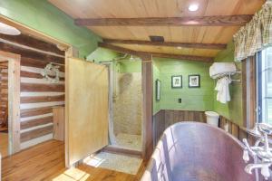 a bathroom with a shower with green walls and a tub at Restored Buchanan Log Cabin on 9-Mile Creek! in Reba