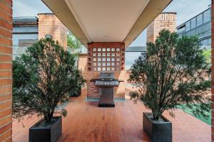 un patio con due alberi e una griglia di Orange Suites by Vibra Bonita a Medellín