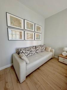 a white couch in a living room with pictures on the wall at Przy plaży Apartament BURZA in Międzyzdroje