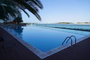 una piscina accanto a una spiaggia con una palma di Sea View, Private Beach and Pool, Palm Jumeirah a Dubai