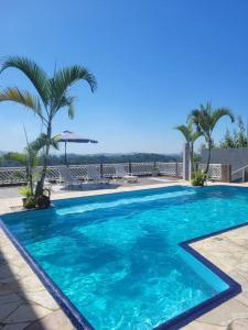 a large blue swimming pool with palm trees in the background at Sitio Arujá com Piscina Aquecida, Quadra e Vista Deslumbrante in Arujá