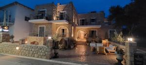 a large house with a stone wall in front of it at Selinopetra Rooms in Elafonisos