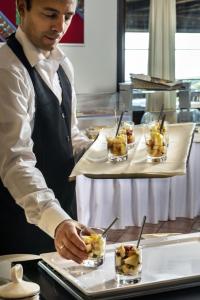 a chef preparing a tray of food in a kitchen at Il Borgo BagaBaga - Exclusive Country Retreat in Castelsardo