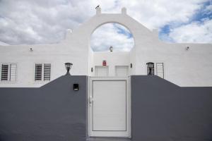 un edificio blanco con un arco sobre una puerta blanca en Calypso Fuerteventura, en Tarajalejo