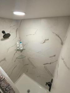 La salle de bains est pourvue d'une baignoire et d'un mur en marbre. dans l'établissement Werner Room 204, Hyland Hotel, à Palmer