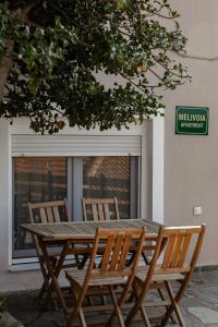 een houten tafel en stoelen voor een raam bij Melivoia Apartment in Ayiá