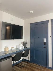 Cette chambre dispose d'une porte bleue, d'une table et de chaises. dans l'établissement Werner Room 204, Hyland Hotel, à Palmer