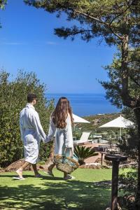 un hombre y una mujer caminando por el césped tomados de la mano en Il Borgo BagaBaga - Exclusive Country Retreat, en Castelsardo