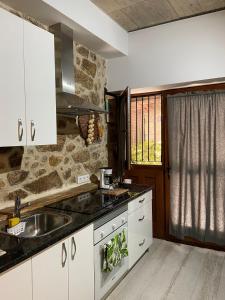 a kitchen with white cabinets and a sink at APARTAMENTO ESTUDIO AS ANDURIÑAS in San Martín de Trevejo