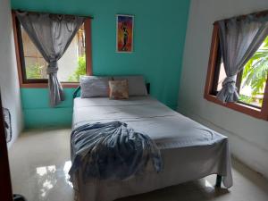 Cama en habitación con paredes y ventanas azules en Casa Anez, en Cabuya