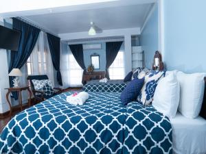 um quarto azul e branco com uma cama e um sofá em Sutton Place Hotel em Roseau