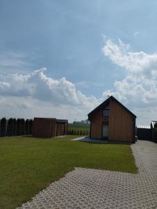 ein kleines Gebäude auf einem Feld mit einem Rasenplatz in der Unterkunft Klimatyzowany domek letniskowy in Mielno